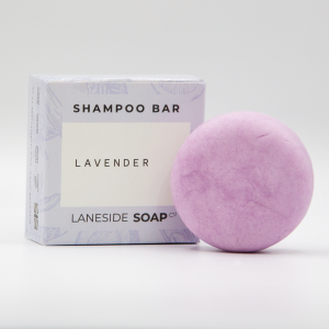 A picture of a Laneside Soap Company Lavender Shampoo bar slightly in front of the packaging that it comes in